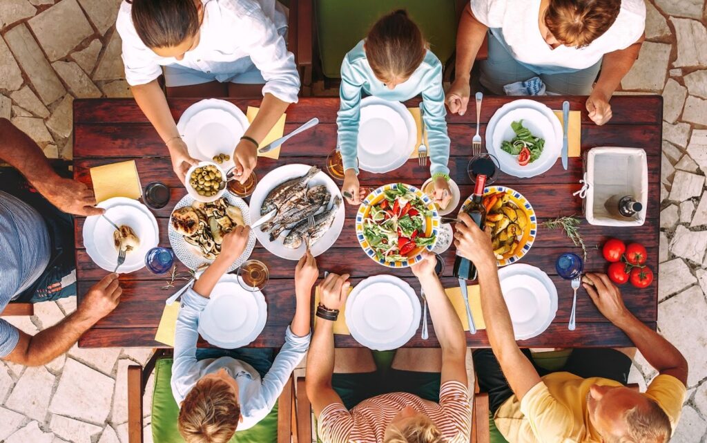 A happy family gathering around a dining table enjoying a gourmet meal prepared by a private chef.